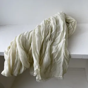 Dettaglio della sciarpa in cotone e lino color crema con pizzo e trama stropicciata
