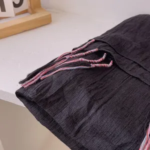 Detailed macro view of black linen scarf fabric with colorful handmade fringe tassels