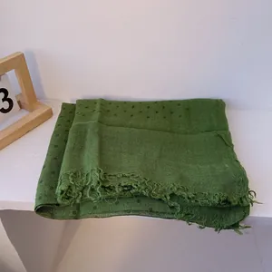 Detail of green linen scarf showing polka dot pattern and frayed edges texture