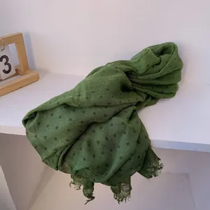 Close-up of dark green linen scarf with polka dots and frayed edge detail