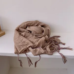 Detailed macro view of khaki cotton linen scarf showing soft crinkle texture and colorful tassels