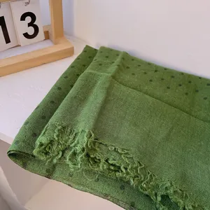 Detail of green linen scarf with black polka dots and delicate fringe edges
