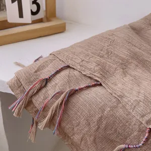 Macro detail of brown linen shawl texture with colorful woven tassel fringe accents