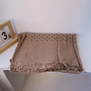 Detail of thin linen shawl featuring black polka dots and natural tassel fringe edges
