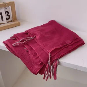 Detail shot of red crinkled linen scarf texture with colorful woven tassel edges