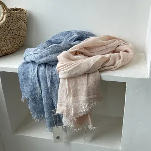 Detailed texture of linen scarf featuring fringed edges in light blue and peach tones