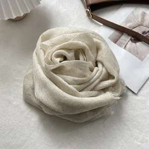 Detail of oat-colored linen scarf with textured fabric and natural fringed edges