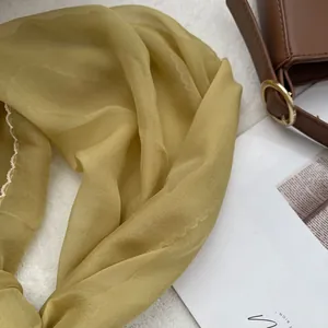 Detail of lightweight olive green scarf with delicate white wavy embroidered edges
