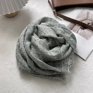 Detailed view of sage green linen scarf with fine grid texture and frayed edges