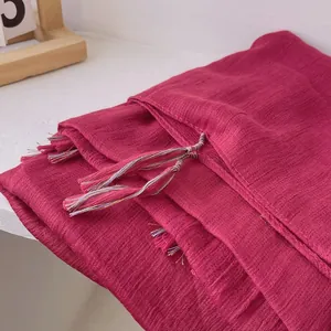 Detail of red cotton linen scarf showing soft pleated texture and colorful tassel fringe