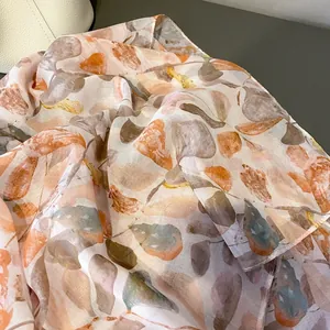 Gros plan d'une écharpe semi-transparente avec imprimé feuilles et texture délicate