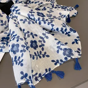 Detail of blue floral print on white cotton-linen scarf with elegant tassel fringe