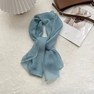 Close-up of light blue chiffon scarf with decorative white scalloped stitched edges