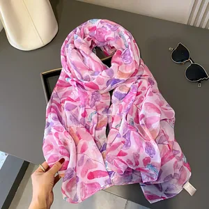 Gros plan détaillé sur le motif de feuilles rose et violette d'une écharpe légère en lin