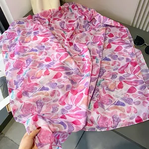 Détail d'une écharpe à imprimé feuilles rose et violet en tissu léger aéré