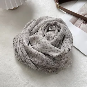 Detail view of a textured linen scarf with floral print and delicate fringe edges