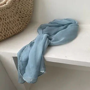 Macro shot of blue lightweight chiffon scarf featuring decorative white contrast stitching