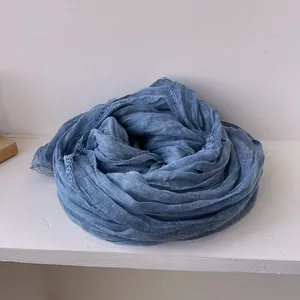 Dettaglio della sciarpa in cotone e lino blu grigio con elegante bordo in pizzo floreale