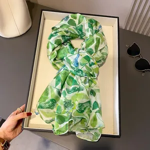 Gros plan d'une écharpe à imprimé feuilles vertes avec lunettes et sac à main blanc
