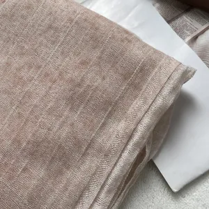 Detail shot of breathable light pink textured linen scarf fabric with soft woven pattern