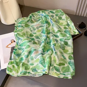 Détail macro du foulard avec imprimé feuilles vertes et bords roulés de qualité