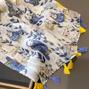 Détail du motif hibou sur l'écharpe avec pompons colorés et texture de tissu léger
