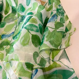 Détail d'une écharpe semi-transparente avec motif de feuilles aquarelle et bords roulés