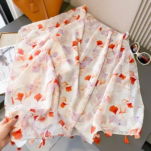 Lightweight ginkgo leaf print scarf with orange tassels and translucent chiffon texture