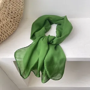 Macro shot of lightweight grass green chiffon scarf with dark green stitching details