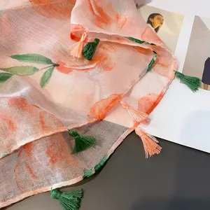 Detail of peach floral linen scarf showing translucent fabric and two-tone tassel edges