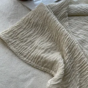 Close-up of pleated cotton linen scarf with elegant lace trim in cream white