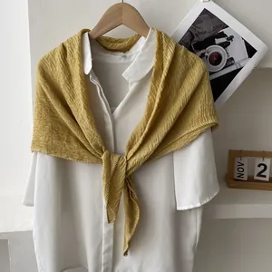 Macro detail of mustard yellow pleated cotton linen scarf with white wavy hem edges