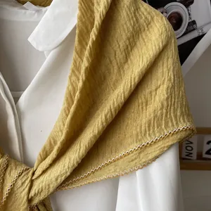 Detail of ginger yellow pleated scarf featuring intricate white crochet lace trim