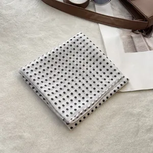 Chic white cotton scarf with black polka dots styled with sunglasses and a leather bag