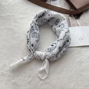 Detailed view of the black and white paisley cotton scarf on a plush background