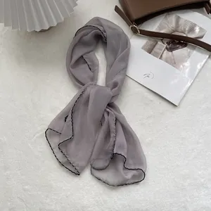 Detailed view of lightweight grey-purple chiffon scarf with fine black stitched edges