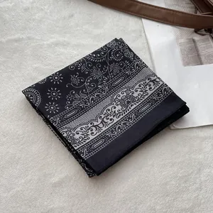 Detailed macro view of black cotton bandana with white floral paisley pattern and stitching