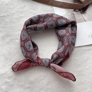 Close-up of vintage geometric pattern and fine stitching on a red silk square scarf