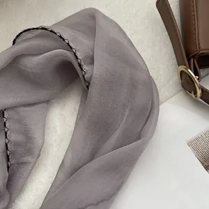 Detail of light purple thin silk scarf with black contrast stitching edge on soft fabric