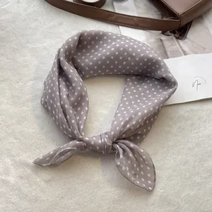 Detail of grey-purple polka dot cotton square scarf tied in a stylish knot on plush carpet