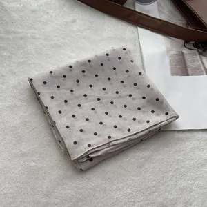 Close-up of beige polka dot cotton scarf with detailed hem edge on white soft texture