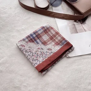 Détail d'un foulard rétro à carreaux et fleurs avec bordure en dentelle sur tapis doux