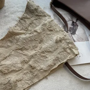 Close-up of beige cotton linen neck scarf with frayed edges and artistic texture