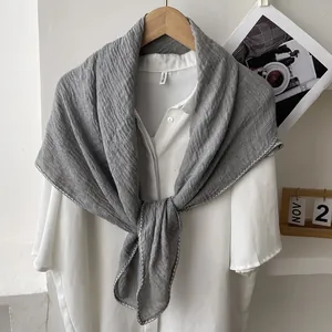 Detail of grey pleated linen scarf with wavy lockstitch edge on a white shirt