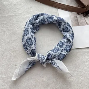 Detail of knotted blue and white floral cotton linen scarf on a leather bag strap