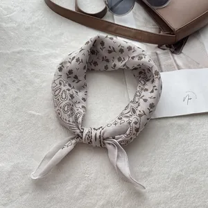 Detailed close-up of beige paisley cotton bandana with floral print on white fuzzy carpet