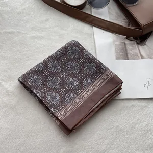 Close-up of folded brown floral bandana with white mandala patterns on a soft rug
