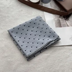 Close-up of a blue polka dot cotton scarf folded neatly with high-quality edge stitching