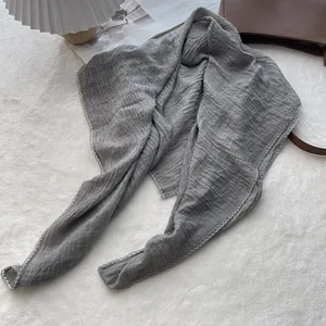 Close-up of grey pleated linen scarf with decorative white zigzag embroidery edges