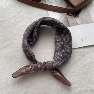 Detail of brown cotton linen scarf with geometric mandala pattern on white plush